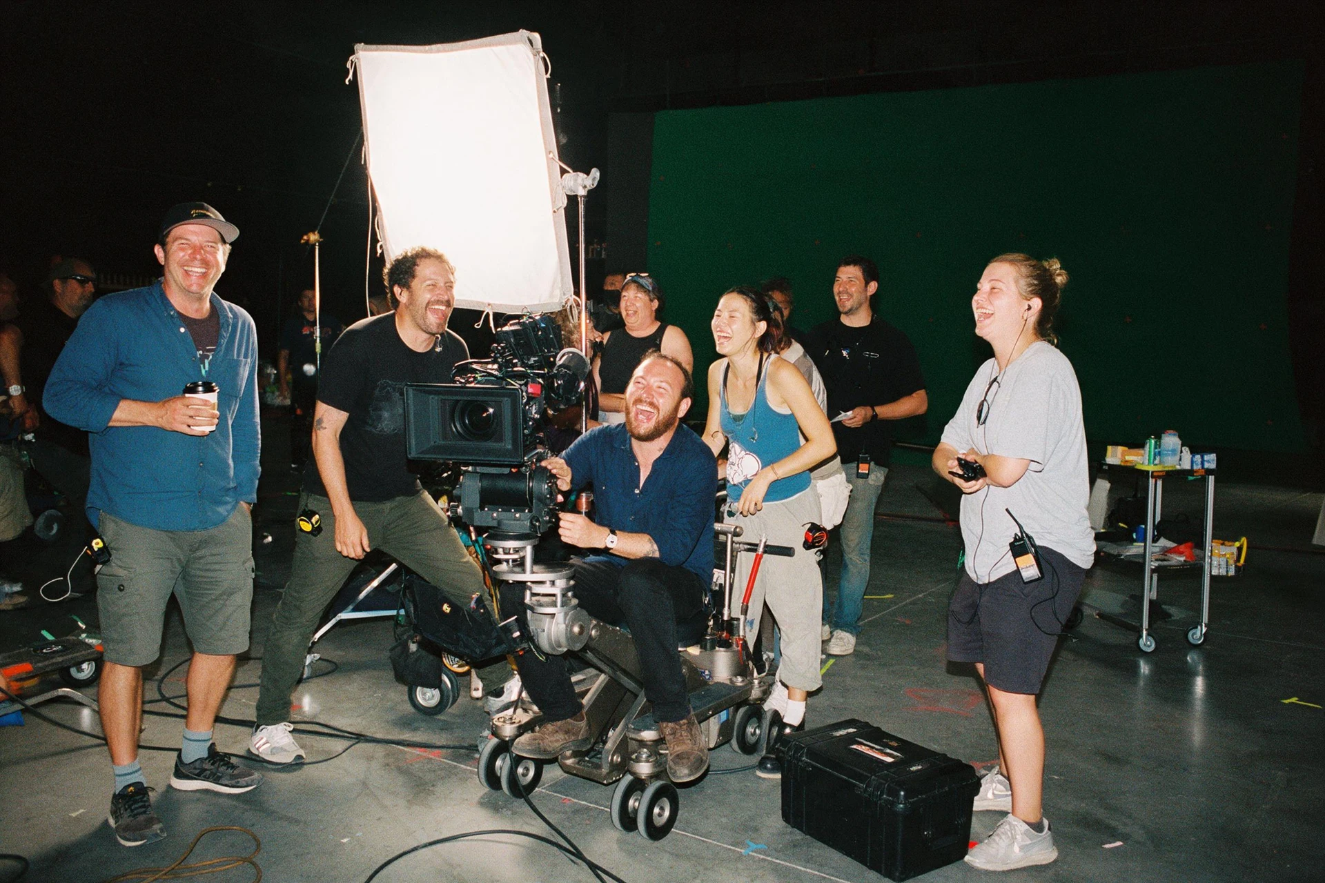 Flash photo of a laughing film crew around a camera dolly